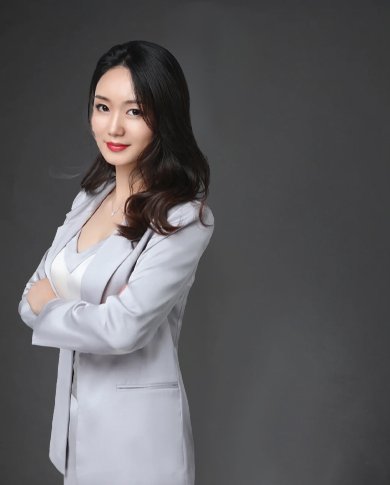 Female professional of magnet factory, in light gray suit, with arms crossed.